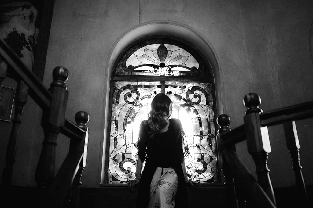 The bride on the stairs before the stained-glass window