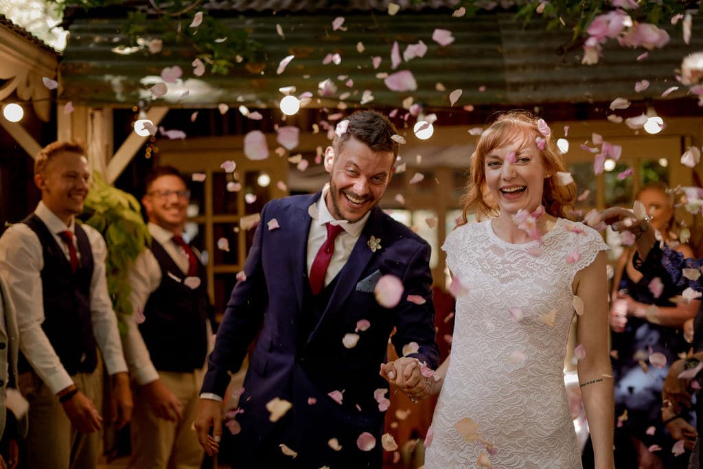 The couple walking out through petal confetti